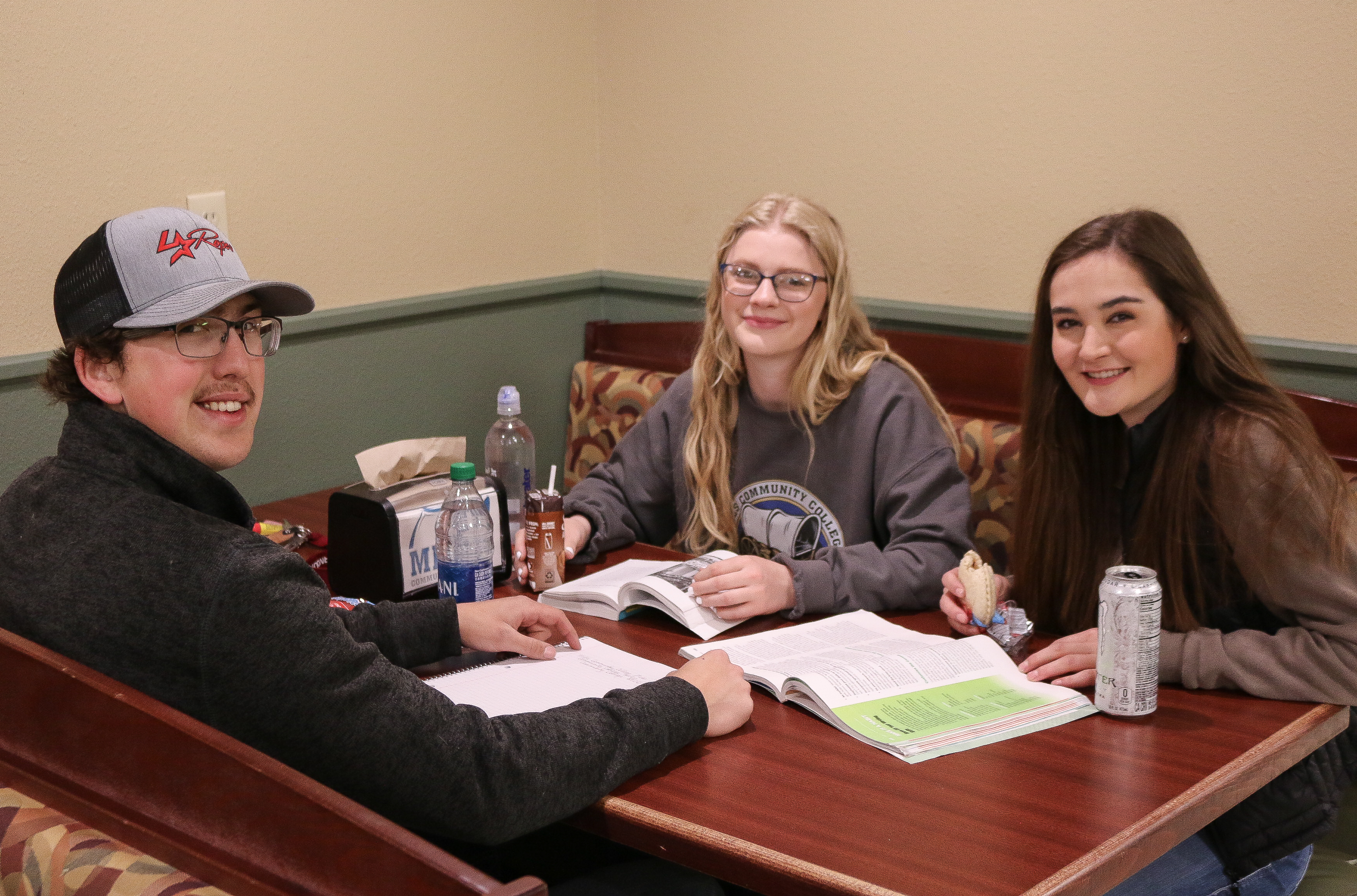 Three students sitting in cafe booth smiling